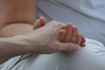 Deux mains réunies lors d'une cérémonie de clôture de yoga à Shantidham, symbole d'écoute, de confiance et de lien.