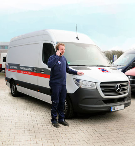 AMF-Bruns Mitarbeiter steht vor dem neuen Service-Mobil mit auffälliger Beklebung.