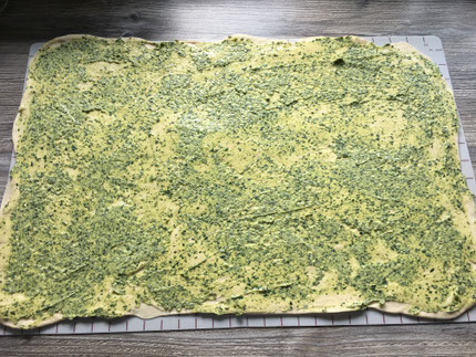 Hefeteig ausgerollt auf einer Backmatte und mit Butter bestrichen