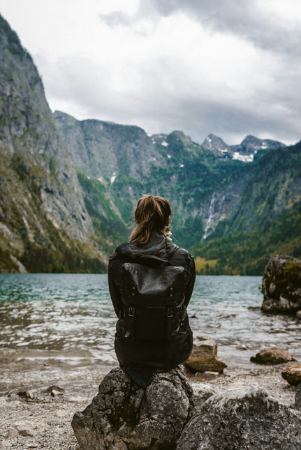 Frau am See, meditierend vor Bergen. 