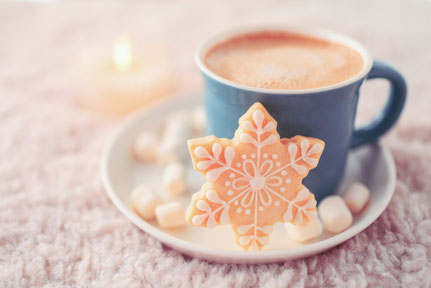 雪の結晶のかたちをしたクッキーが添えられたコーヒーのマグカップ。