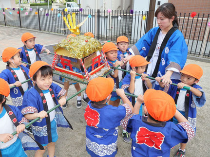夏祭りで子どもがおみこしを担いでる様子