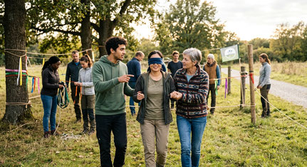Teambuilding — Eine Person wird mit verbundenen Augen von zwei Teamkolleg:innen durch einen Parcours geführtours im Freien