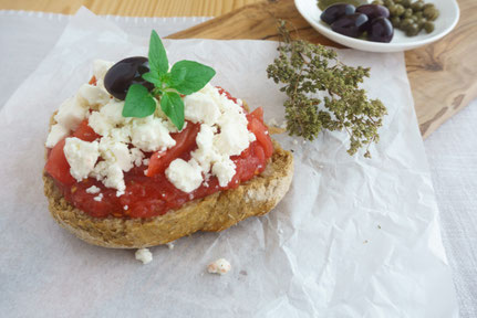 Brot mit Tomate und Feta und Oliven in einer Schüssel auf einem Brett