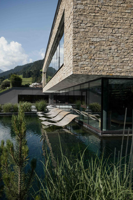erfrischender Badeteich im Saunabereich mit Liegestühlen im Wasser - NESSLERHOF in Großarl • 5-Sterne-Wellnesshotel im Salzburger Land