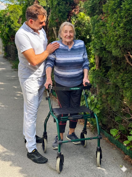 Physiotherapeut Roman Fenz unterstützt eine ältere Patientin mit Rollator beim Hausbesuch in Wien.