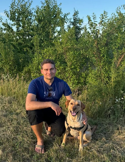 Physiotherapeut Roman Fenz von Physiotherapie Essling mit seinem Hund im Grünen. 