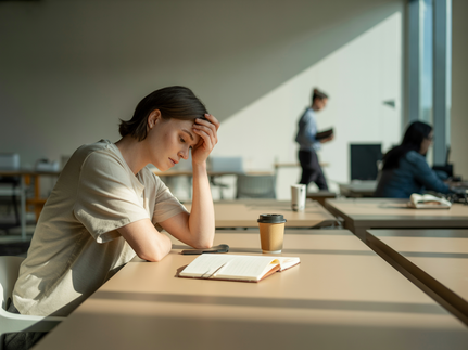 Frau sitzt erschöpft am Schreibtisch_Burnout