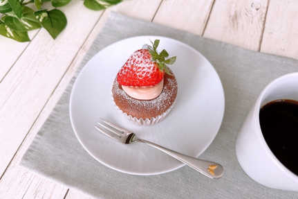いちごとクリームがのったカップケーキのお皿。フォーク。コーヒーの入ったマグカップ。