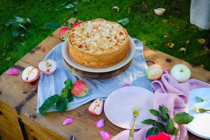 パソコンのキーボードの前に置かれた手紙の入った封筒とボールペン。オレンジピンクのバラとガーベラの花。