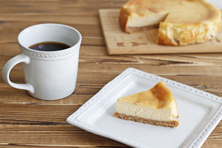 ホールサイズから切り分けられたチーズタルト。コーヒーの入ったマグカップ。