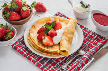 いちごと生クリームがたっぷりのクレープのお皿。チェック柄のナプキンとフォーク。