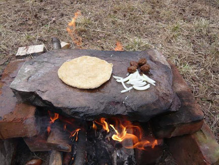 Cooking bread and vegetables on a flat stone over the fire