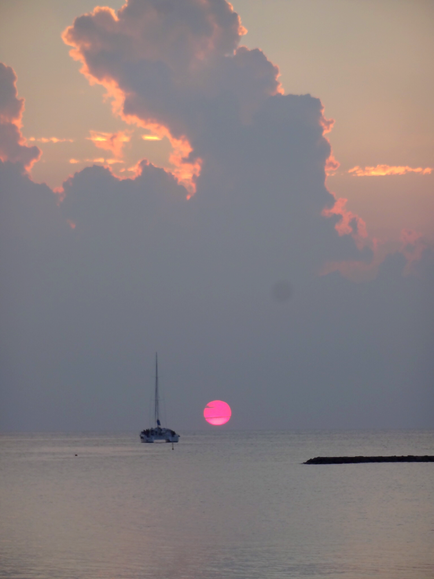 8月18日沖縄ブセナテラスのビーチでのサンセットヨガの時見た夕日。厚い雲を突き通してさくらんぼ色の太陽が浮き上がる様は、幻想的だった･･･ヨガの先生もひとつとして同じものがない夕日にいつも感動するのだという･･･。