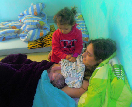 Mutter im Wochenbett mit Baby und großer Schwester