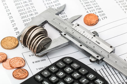 Das Budget muss genau kalkuliert werden. Das Geld ist in einem Messgerät eingespannt und wird mit dem Taschenrechner nachgerechnet
