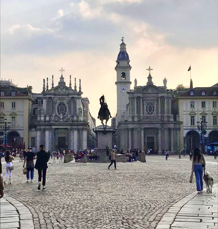 piazza di Torino con statua di uomo a cavallo e chiesa di sfondo, al tramonto