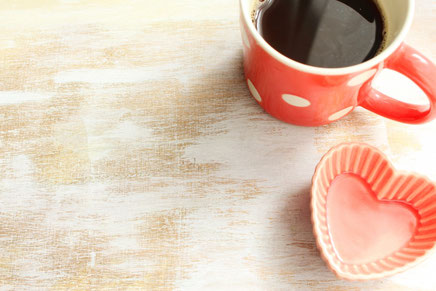 コーヒーの入った水玉模様のマグカップ。ハート形の器。