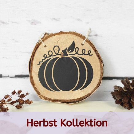 Holzornament mit schwarzem Kürbis, Blatt und Ranke, umgeben von Zapfen – Teil einer herbstlichen Deko-Kollektion.