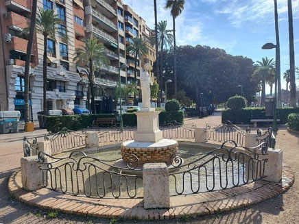 La Fuente de la diosa Flora en la ciudad de Valencia, sostiene una flor en su mano derecha, sobre un pedestal y dentro de un estanque circular, rodeada por una estructura de ladrillo.