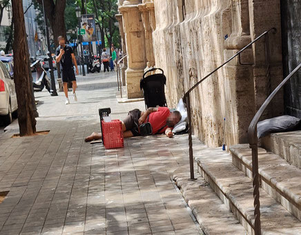 Este indigente en Valencia, hace lo mismo que otros. Pasa la noche en la puerta de la iglesia para que no le quiten el sitio. Y sus necesidades, pues las hace entre medio de los coches aparcados.
