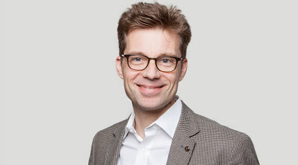 Das Bild zeigt Jörg Dittmann mit kurzen blonden Haaren und Anzug, der in die Kamera lächelt.
