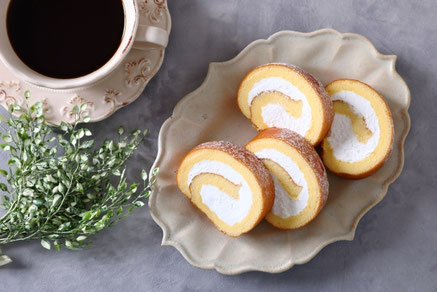 カットされた生クリームたっぷりのロールケーキが盛り付けられたお皿。コーヒーの入ったカップ＆ソーサ。