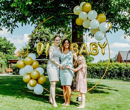 Schwangere Frau steht mit ihren Töchtern auf ihrer Babyparty