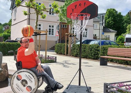 Rollstuhlbasketballer mit Basketball und Korb