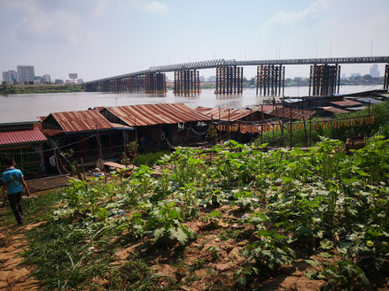 Vue du pont métallique qui enjambe le Tonlé Sap pour relier Phnom Penh à Chrui Changvar, et de quelques maisons flottantes.