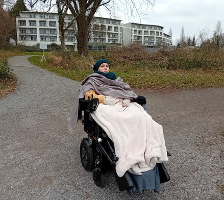 Ich, im E-Rollstuhl sitzend, vor der Klinik in Konstanz