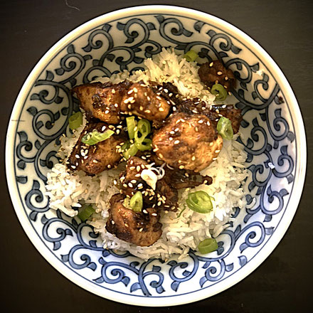 white rice topped with chicken in a blue and white patterned bowl