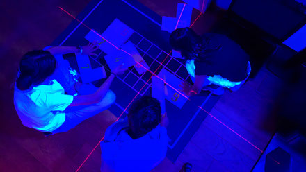 Gemeinsam rätseln die Jugendlichen und Kinder im Escape Room in der Region Luzern. Ein Laserkreuz leuchtet auf ein Puzzle. Das Escape Game findet indoor statt und ist eine Idee als wetterunabhängige Kinderaktivität an einem Regentag.
