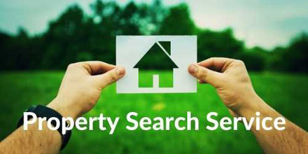 Someone holding a cut out of a house while looking at a green garden