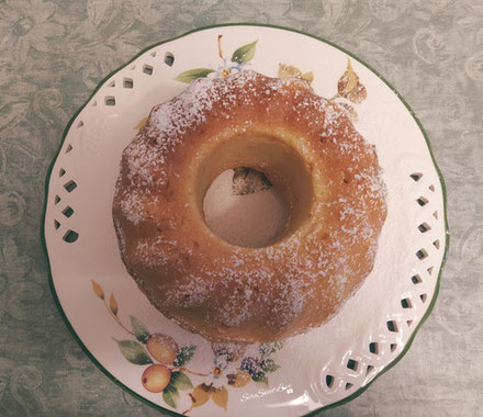 Ciambellone ricotta e limone con zucchero a velo servito su un piatto da portata