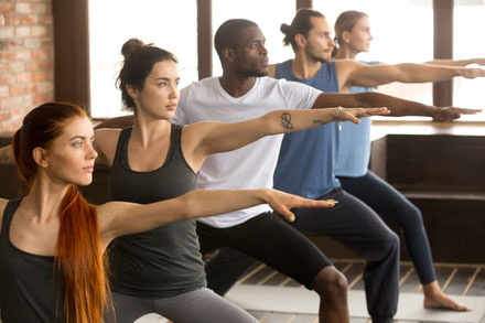 Bild von einer Yogastunde. Erwachsene führen eine Übung aus. 
