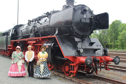 Biedermeier vor einer großen Dampflokomotive