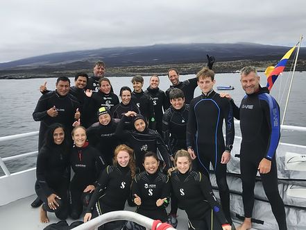 A photo of 20 scuba divers in wetsuits on a dive liveaboard in the Galapagos Islands