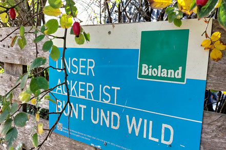 Unser Acker ist bunt und wild steht auf einem blauen Schild mit dem Bioland-Logo