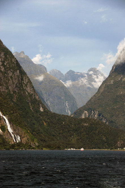 The staggering view back to the boat terminus at Milford Sound and the peaks of the Darran Mountains with their immensely steep slopes carvbed out of hard Plutonic rocks. Bowen Falls to the left.