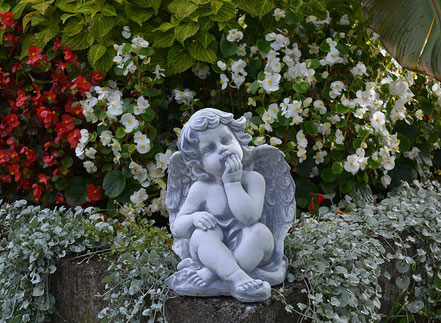 Engel Statue aus Weißbeton im Garten mit Rosen und weißen Pflanzen