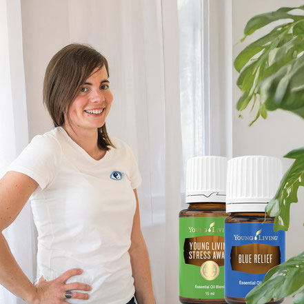 Michelle Weissenböck vor einem weißen Vorhang, zudem zwei Beispielöle von Young Living. 