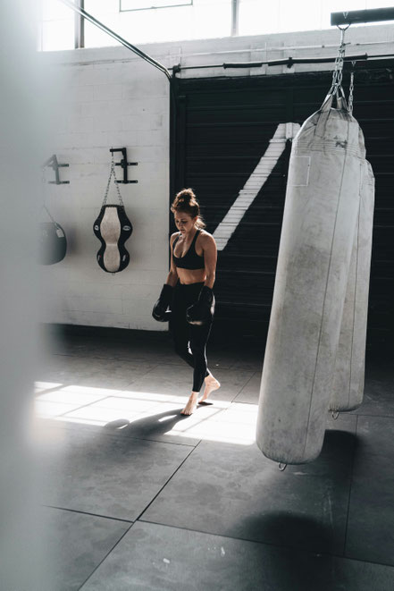 Frau mit Boxhandschuhen im Training am Boxsack