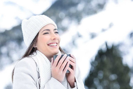 Frau im Urlaub in den Bergen bei Schnee mit warmer Tasse