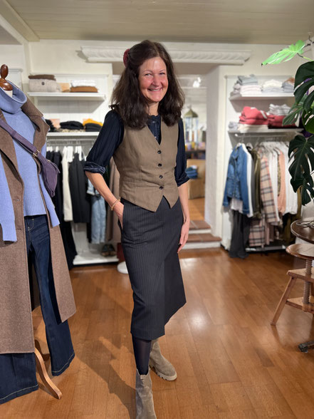 Beate trägt klassisches Herbst-Outfit mit Weste, Midirock und Stiefeletten in der Boutique Vergissmeinnicht in Miesbach.