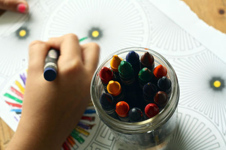 Photographie d'un pot à crayons et d'un enfant faisant un coloriage tirée d'une banque d'image libres de droits