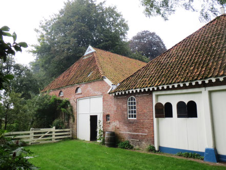 De achterzijde van de 19de-eeuwse landbouwschuur (links) en het koetshuis uit 1796 met de dubbele wagenpoort.