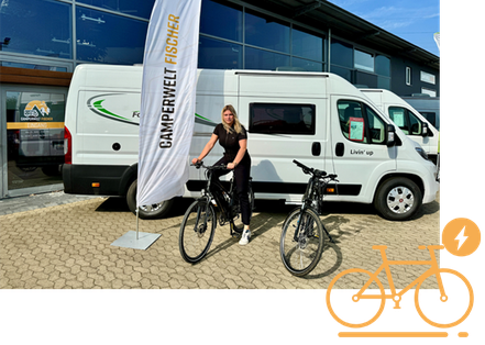 Eine Mitarbeiterin der Camperwelt Fischer auf einem E-Bike, im Hintergrund Camper und das Firmengebäude in Celle.