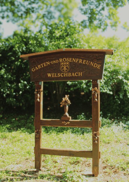 Das hölzerne Eingangsschild vom Rosengarten Welschbach, begrüßt die Besucher 