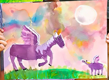 Das bunte Gemälde wurde von einer Sechsjährigen in meinem Malkurs gemalt. Es zeigt zwei lilane Einhörner - Mutter und Kind vor einem bunten Himmel mit rundem Mond. Kind